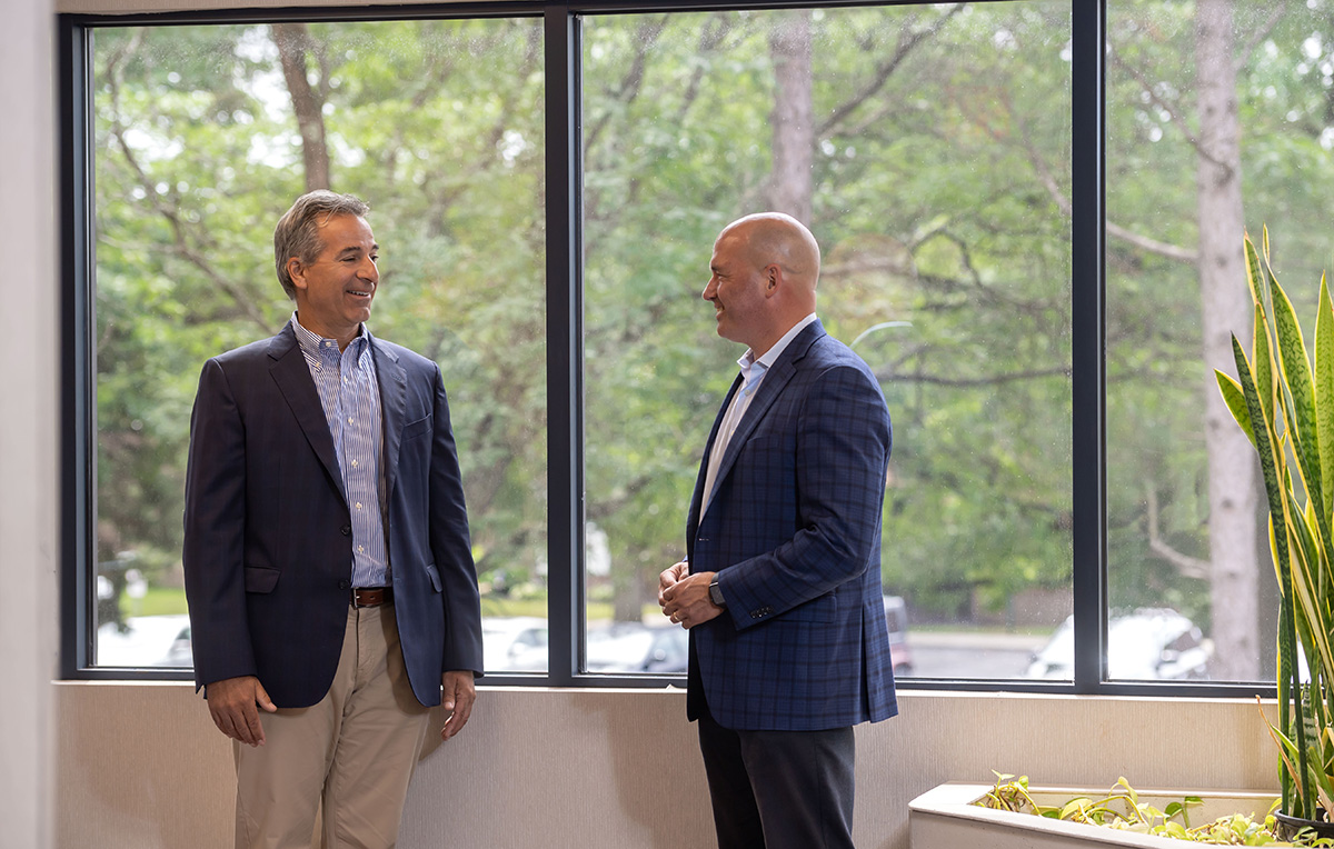 Two men talking in front of an office window